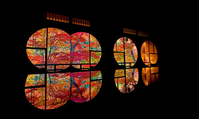 Autumn leaves seen through the round window of a traditional Japanese house and their reflections in Arashiyama of Kyoto, Japan.