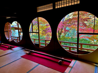 Autumn leaves viewed through the round window of a traditional Japanese house in Arashiyama of Kyoto in Japan.