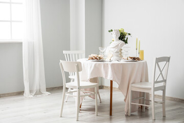 Table setting for Nobel prize day with Greek statuette and roses in light room