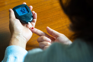 Woman's hands checking diabetes and hyperglycemia with digital blood sugar meter. Healthcare and...