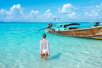 Woman Standing in Crystal Clear Water Near Traditional Thai Longtail Boat