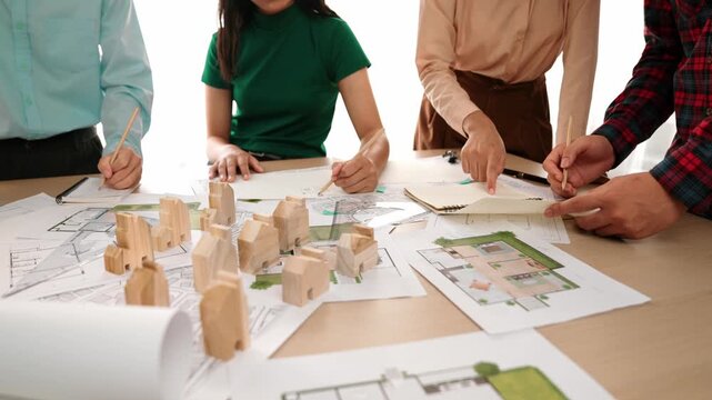 Smart architect and safety engineer discussion about building blueprint on table with architectural document, measurement tools and wooden block scatter around at modern office. Closeup. Delineation.