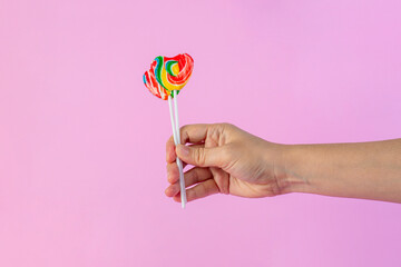Sweets, two lollipops in hand, on pink background