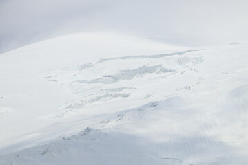 White clouds envelop Mount Elbrus on a sunny summer day