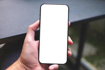Mockup image of a man holding mobile phone with blank white screen in cafe
