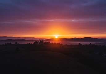 Obraz premium Vibrant sunrise over rolling hills creating a scenic landscape view