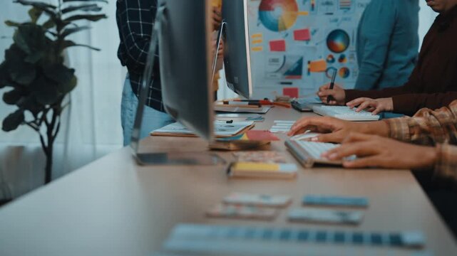 Collaborative atmosphere in a modern office showcasing professionals engaged in discussion around computers and documents, highlighting creativity and teamwork in action. SACTR