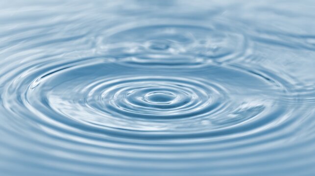 Gentle droplets shaping delicate water circles under a peaceful blue atmosphere.