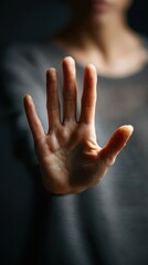 Woman raising open hand in gesture of refusal or protection against dark background, symbolizing Istanbul Convention