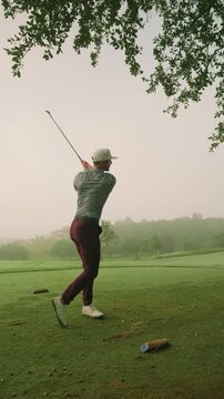 Male golfer hits controlled three quarter swing iron off tee on foggy morning, ball launching clean through misty fairway for clean, cinematic golf shot