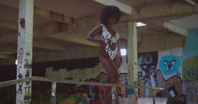 A dark-skinned girl in a bikini, her Afro bouncing, navigates the bowls and ramps of an indoor skate park.