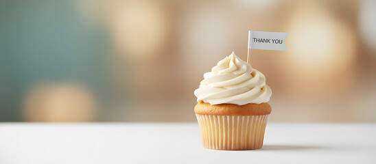Cupcake with cream frosting and thank you flag on white table  