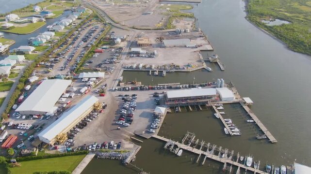 Drone backtracks over the Grande Isle Marina, showing docks, boats, boat slips, and marine infrastructure. Tarpon Rodeo Event Center is the venue for the Strong Island Music Festival.