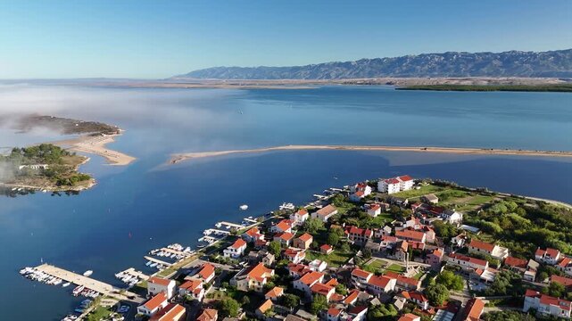 Drone glides backward over Nin, Croatia&mdash;Velebit mountains, Adriatic blue, Queen&rsquo;s Beach, rooftops, and salt fields in autumn morning light.