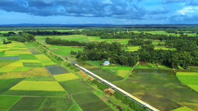 Aerial view of a train passing through lush green fields in bangladesh