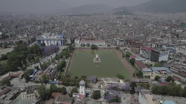 Drone view of Kathmandu Valley featuring Rani Pokhari, Ghantaghar, and blooming Jacaranda flowers, showcasing the valley&rsquo;s rich heritage, colors, and timeless urban charm.