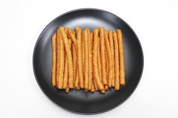 Crispy pork stick snack on black plate, isolated