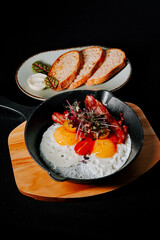 Delicious breakfast served in a skillet with eggs, bacon, and toast on a wooden board