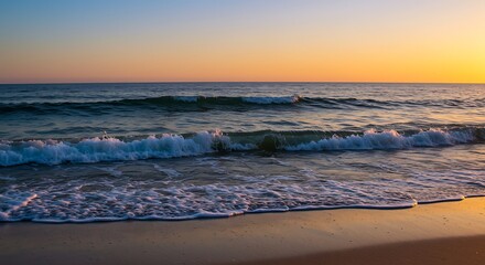 Fototapeta premium Gentle waves rolling onto a sandy beach at sunset, bathed in warm golden light