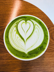 Healthy green hot matcha in a white heart-shaped milk form green tea drink