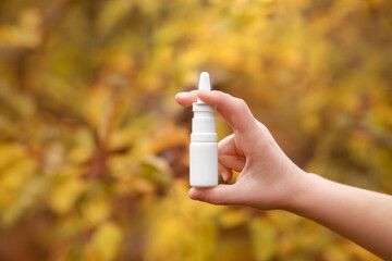 Nasal Spray in Hand in Autumn Fall Leaves Background as Necessary Help for Respiratory Diseases and Allergies.