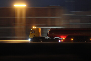 A tractor-trailer with a tanker truck moves along a night road