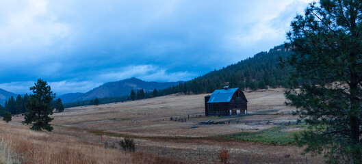 Panoramic view of old barn in the middle of farm in autumn blue hour