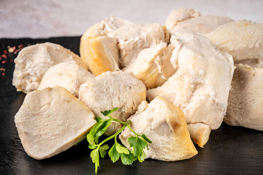 Boiled chicken breast pieces on dark slate