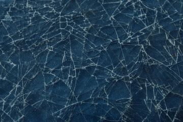 Pattern on cracked glass. Damage to glass. Broken or damaged glass wall with blue background.