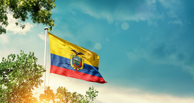 Ecuador national flag waving in the sky behind the tree. The flag blowing with beautiful sunlight. Ecuador national national flag for independence day.