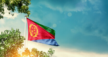 Eritrea national flag waving in the sky behind the tree. The flag blowing with beautiful sunlight. Eritrea national flag for independence day.