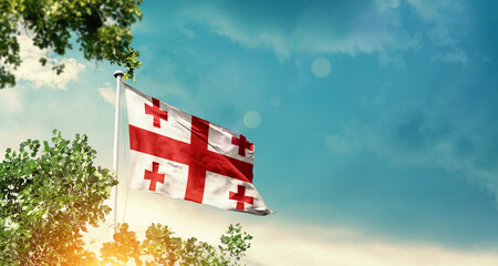 Georgia national flag waving in the sky behind the tree. The flag blowing with beautiful sunlight. Georgia national flag for independence day.