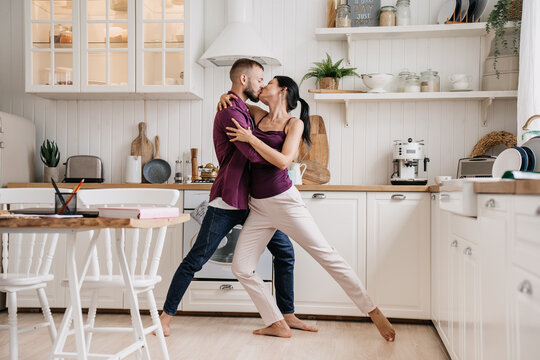 Sharing a passionate kiss in the kitchen, the couple's love and joy ignite the space, capturing a timeless romantic moment.