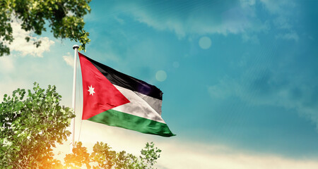 Jordan national flag waving in the sky behind the tree. The flag blowing with beautiful sunlight....