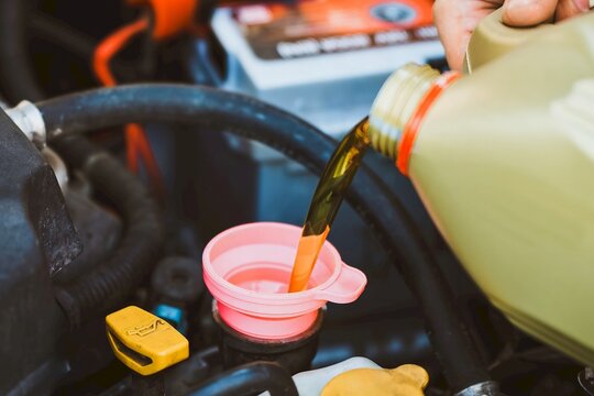 Hand refilling oil in vehicle engine - Powered by Adobe