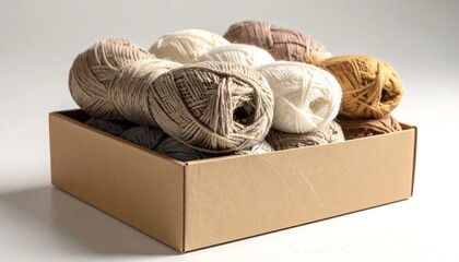A box full of yarn balls in various neutral colors on a white surface, warmly lit
