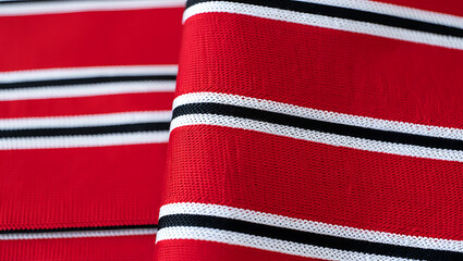 A close-up of a traditional sadu textile, showing the distinct red, black, and white striped pattern.