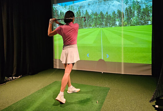 Indoor golf practice session featuring a female golfer using a simulator in a woodland