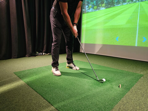 Indoor golf training session with player preparing to take a swing at a virtual course concept - Powered by Adobe
