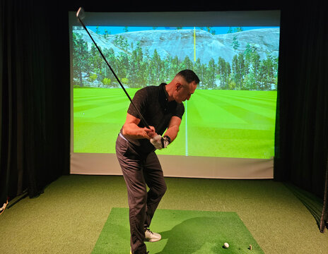 Indoor golf swing practice at a virtual driving range with a digital background scene concept
