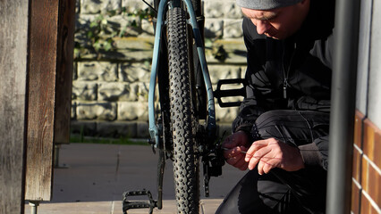 A man's daily chores around the house. A man repairs a bicycle in the yard.
