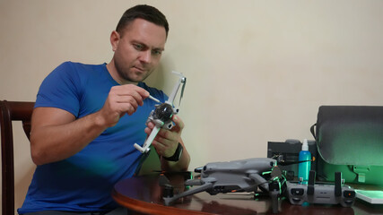A man repairs drones at home. Working on quadcopters. The man tightens fasteners with a screwdriver.