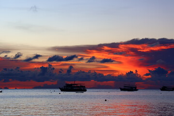 Obraz premium Sunset boat floating over the peaceful tropical sea