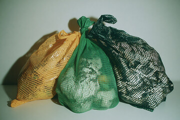 Top-down flat lay of green eco-friendly produce bags, neatly arranged on neutral background, highlighting sustainable shopping, reusable materials, clean minimalist composition.