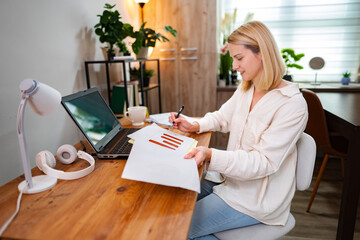 Focused woman analyzes data while working in a cozy home office environment