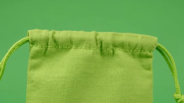 Close up of a green drawstring bag on a green background.