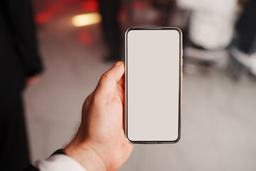 Hand holding a smartphone with blank screen in a party