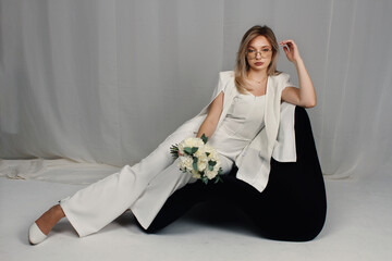 Portrait of a girl in a white suit holding flowers. Female portrait.	