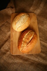 Close-up of two baked rolls, highlighting the crispy crust and soft interior. The rustic texture of the burlap background enhances the feeling of artisan, wholesome baking