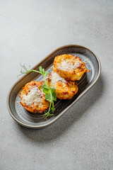 Three delicious baked potato cakes sit on a modern plate, garnished with herbs and cheese